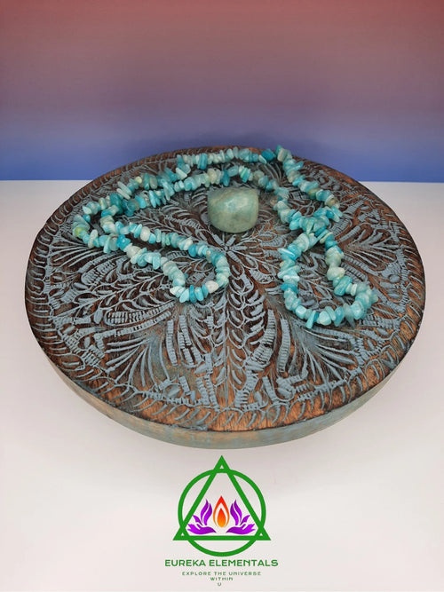 Amazonite Necklace and Crystal resting on a wooden stand with a red and blue ombre backdrop.