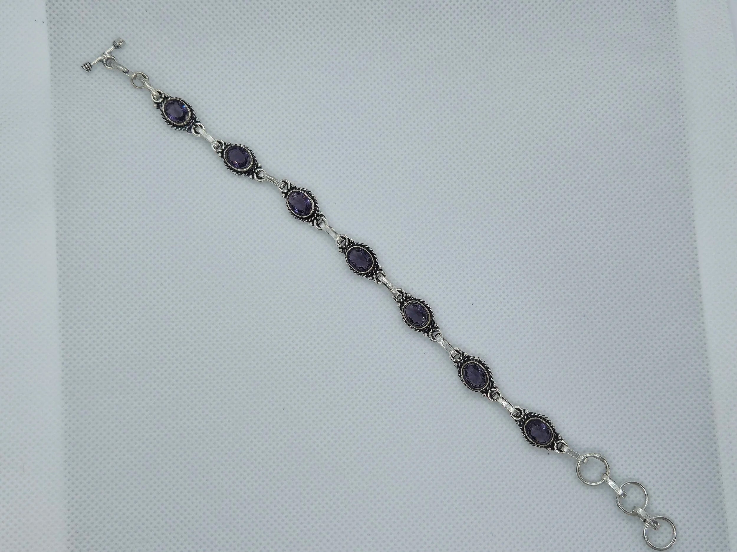 One Artisan Amethyst Silver Toggle Bracelet laid out over a white cloth background. 