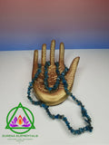 Blue Apatite Necklace resting on a golden hand with a red and blue ombre background. 