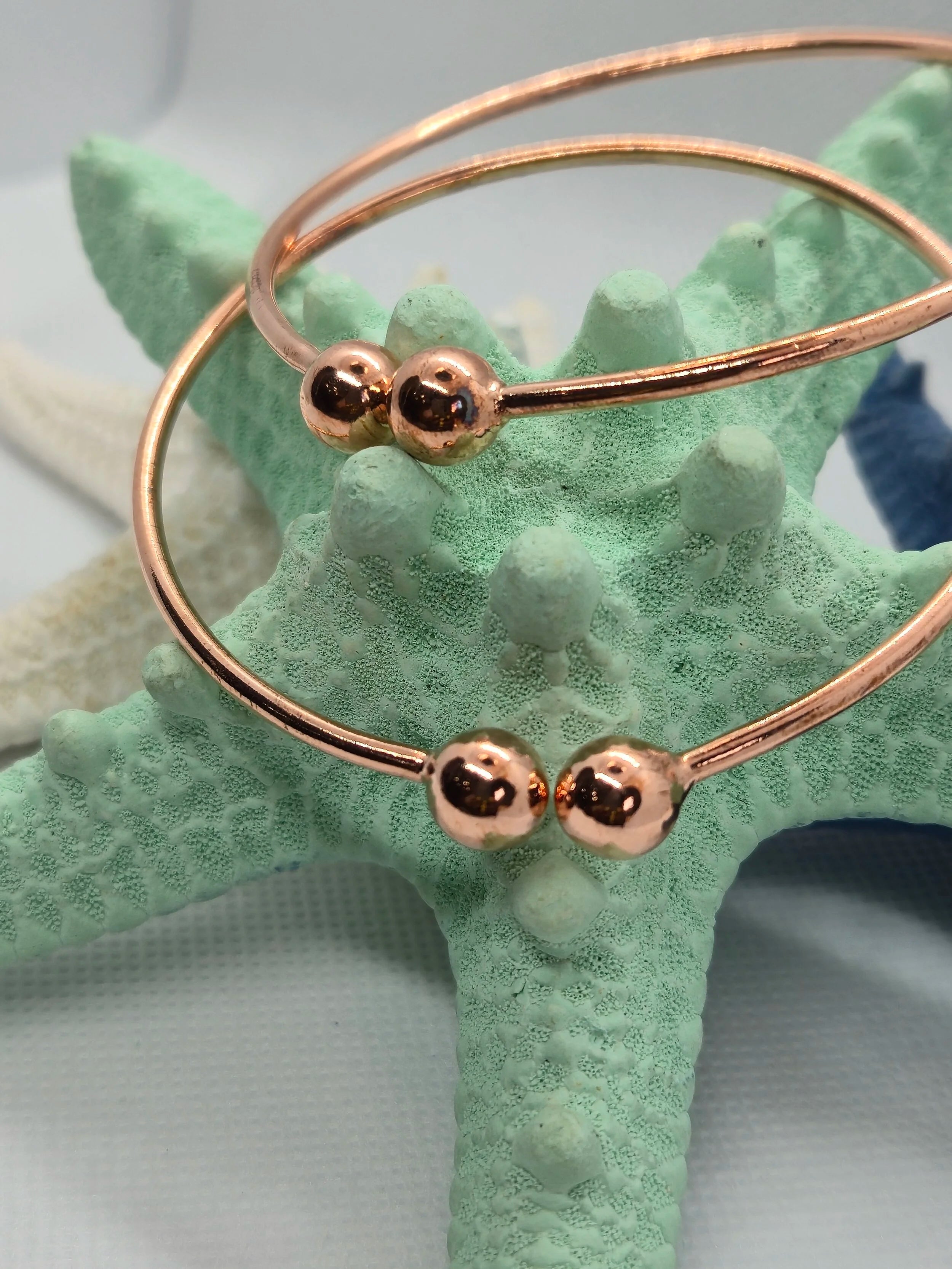 Two Heavy Copper West Indian Bangles dangling off a an aquamarine starfish.