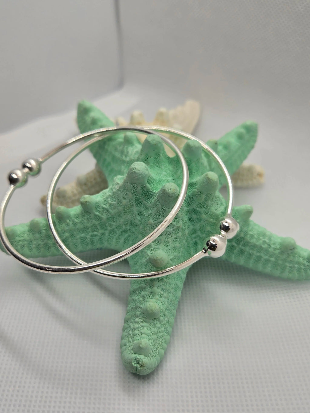 Two Heavy Silver West Indian Bangles dangling off a an aquamarine starfish. 